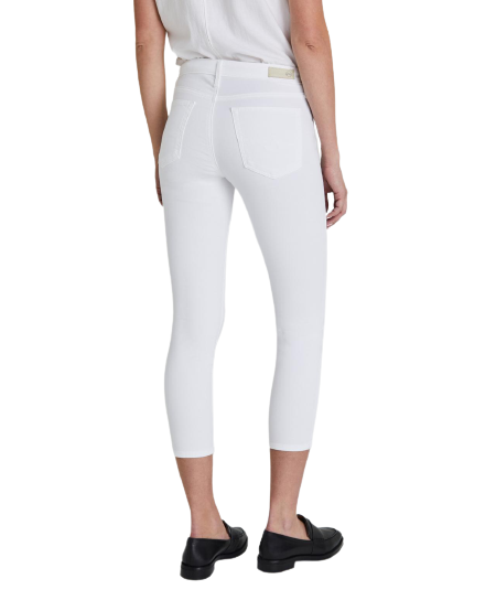 A person is seen from the back wearing a white sleeveless top, Prima Crop Luscious Super Stretch Sateen pants by AG Jeans in white, and black shoes.