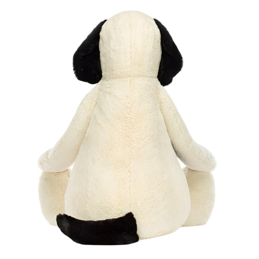 Giant back view of the Jellycat Bashful Black & Cream Puppy, a plush toy with soft cream-colored fur, distinct black ears, and a matching black tail. This cuddly companion is made from plush materials and has a polyester inner filling for added softness.