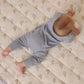 A baby in a light blue Quincy Mae Baby and Kids' Long Sleeve Tee with shoulder snaps lies on their stomach on a quilted blanket featuring a hot air balloon pattern.