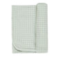 The Quincy Mae Baby Bamboo Swaddle is a soft, light-colored blanket with a simple grid pattern and stitched edges, shown partially rolled at one end.