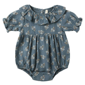 The Quincy Mae Baby Girls' Collared Romper features short sleeves, a ruffled collar, and a blue fabric with a white floral print and ruffle details.