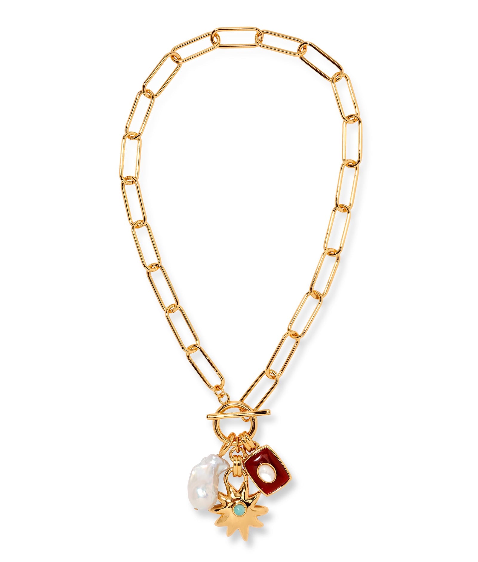 The Helios Charm Necklace by Lizzie Fortunato features a gold chain with large links, accented by a white freshwater pearl, a red rectangular charm, and a gold sunburst charm set with a small green stone.
