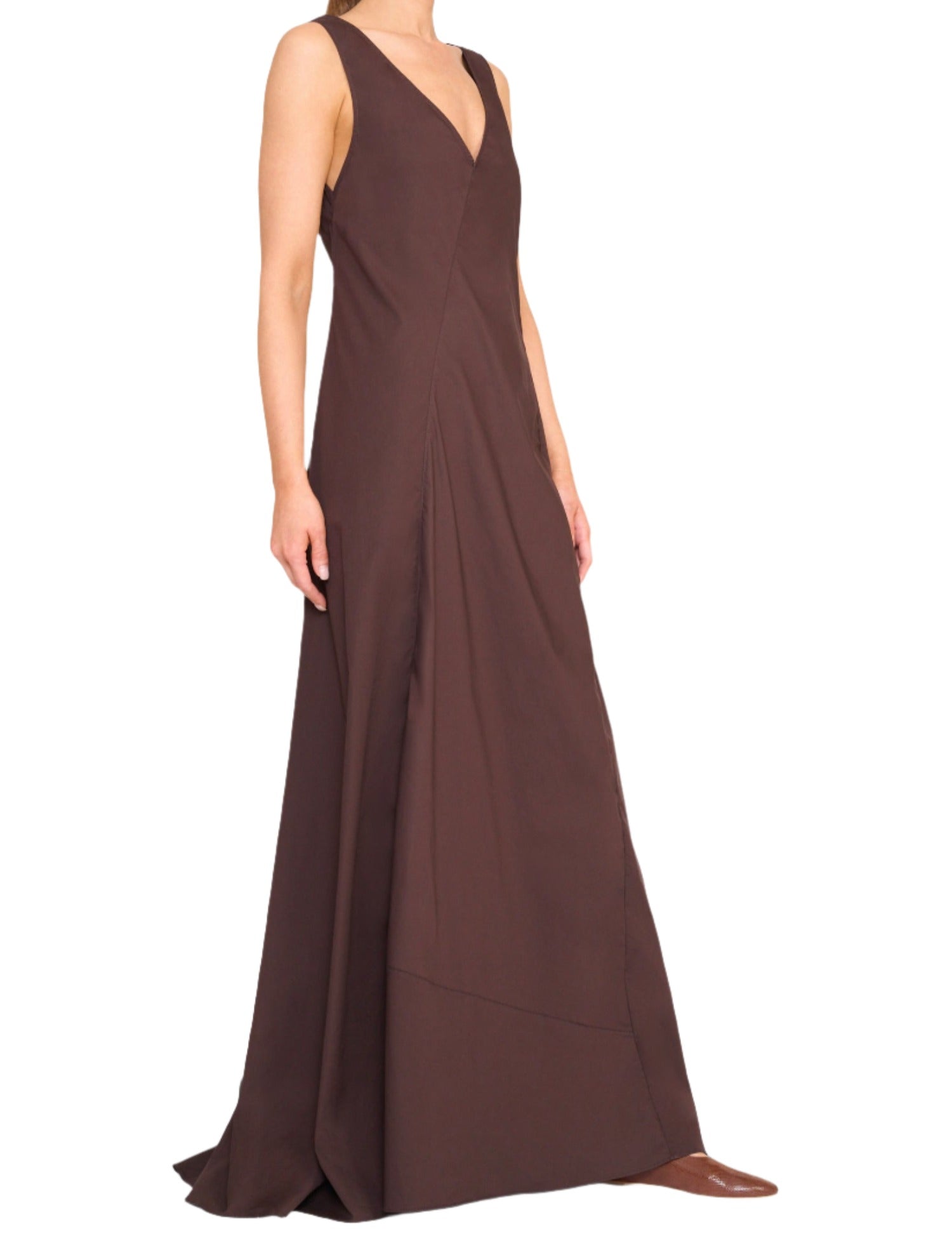 Person wearing the Staud Roma Dress, a sleeveless, dark brown, V-neck gown that extends to the floor, with a fitted bodice and flowing skirt—truly a classic day-to-night dress by Staud.