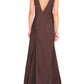 A person stands wearing a sleeveless, deep V-neck, full-length brown dress, viewed from the back against a plain white background. This Staud Roma Dress by Staud transitions effortlessly as a classic day to night dress.