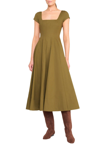 A person is wearing a knee-length, olive green Staud Wells SS Dress with short sleeves and a square neckline, featuring a corset-style panel, paired with brown knee-high boots.