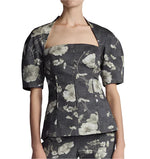 A person wearing the Lela Rose Bustier Top, a structured piece featuring a floral pattern, large sleeves, and a square neckline.