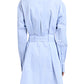 Rear view of a person in the Proenza Schouler Viola Dress, a knee-length blue and white striped cotton-silk poplin with long sleeves, collared design, and cinched at the waist with a matching D-ring fabric belt.