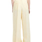 Back view of a person wearing Proenza Schouler's light beige Jules Pant, made from linen viscose, paired with a white top against a white background.