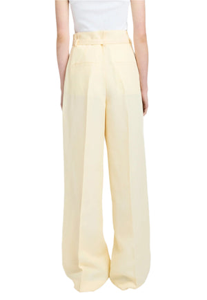 Back view of a person wearing Proenza Schouler's light beige Jules Pant, made from linen viscose, paired with a white top against a white background.
