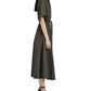 A woman in profile wears the Proenza Schouler Scottie Dress, a dark green eco stretch linen piece with short sleeves and a self-tie waist belt, paired with black lace-up shoes.