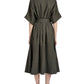 A woman is shown from the back wearing the Proenza Schouler Scottie Dress in olive green Eco Stretch Linen with a self-tie waist belt and black heeled sandals, set against a white background.