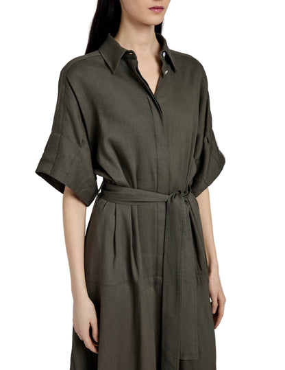 A woman wearing the Scottie Dress by Proenza Schouler, an olive green collared shirt dress in Eco Stretch Linen with short sleeves and a self-tie waist belt.