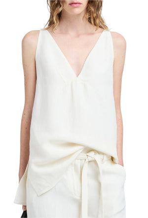 A woman wears the Proenza Schouler Mitchell Top, a sleeveless V-cut tank in off-white Cotton Viscose Linen with a draped front, paired with matching high-waisted tie-waist bottoms.