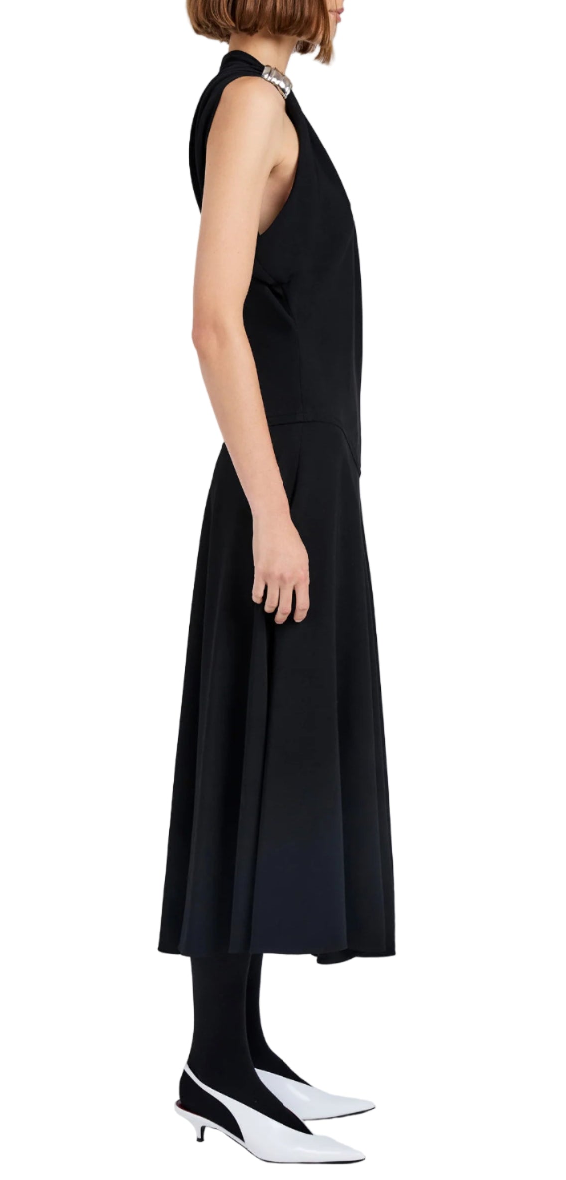 A woman in profile wears the Proenza Schouler Rue Light Matte Double Crepe Dress, styled with black tights, white heels, and a pearl necklace against a plain white background.