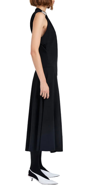 A woman in profile wears the Proenza Schouler Rue Light Matte Double Crepe Dress, styled with black tights, white heels, and a pearl necklace against a plain white background.