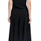 A woman faces away, wearing the Proenza Schouler Rue Light Matte Double Crepe Dress in black, paired with black tights and white-heeled shoes.