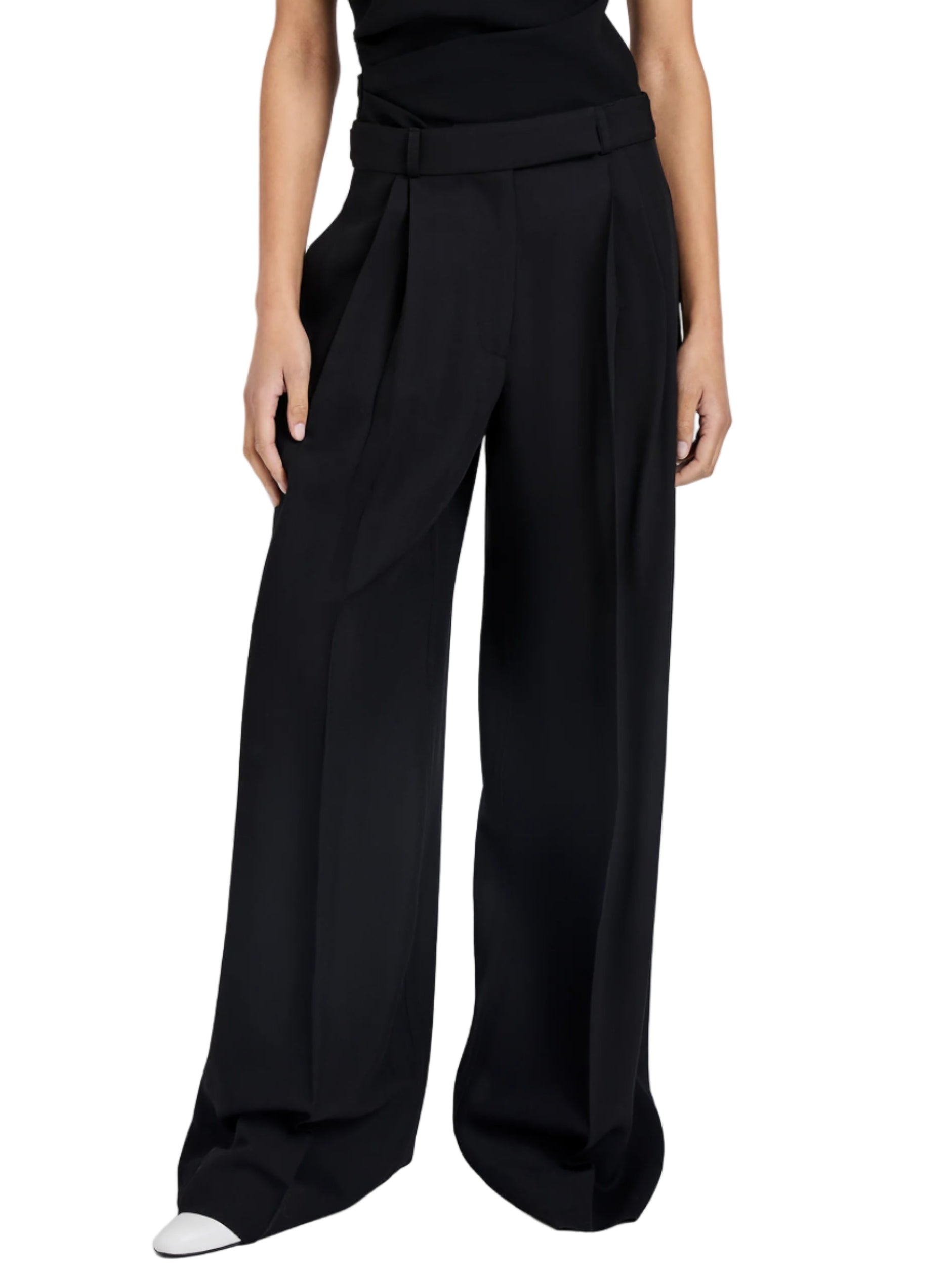 A person wears the Proenza Schouler Patricia Classic Twill Pant, a high-waisted, pleated wide-leg style, paired with a black top; only their lower torso and legs show off the tailored silhouette.