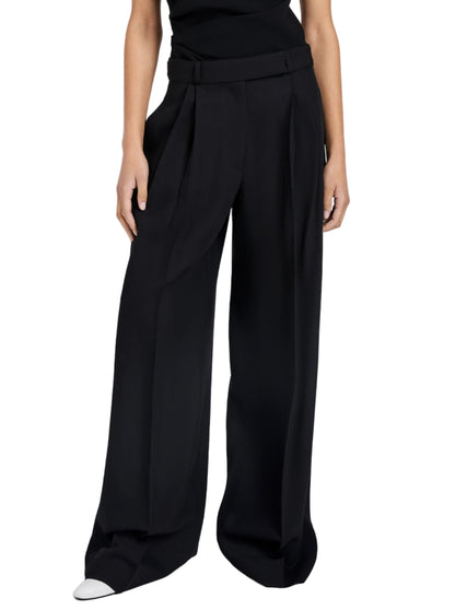 A person wears the Proenza Schouler Patricia Classic Twill Pant, a high-waisted, pleated wide-leg style, paired with a black top; only their lower torso and legs show off the tailored silhouette.