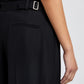A person wears the Proenza Schouler Patricia Classic Twill Pant in black, featuring wide legs and a side buckle detail, shown from the waist down with their right arm at their side.