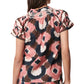 A person wearing the Rosie Top by Figue, showcasing a pink, brown, and black abstract pattern featuring crochet detail on the back and a smocked neckline for added flair.