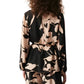 Rear view of a person with curly hair wearing the Kasey Tunic by Figue, featuring long sleeves, a black and beige abstract pattern, a stylish boat neckline, and a waist tie.