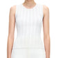 A woman wears the Adam Lippes Brynn Top Compact Jacquard, a sleeveless rib-stitch top with subtle vertical patterns and a fitted bodice, paired with white bottoms against a plain background.