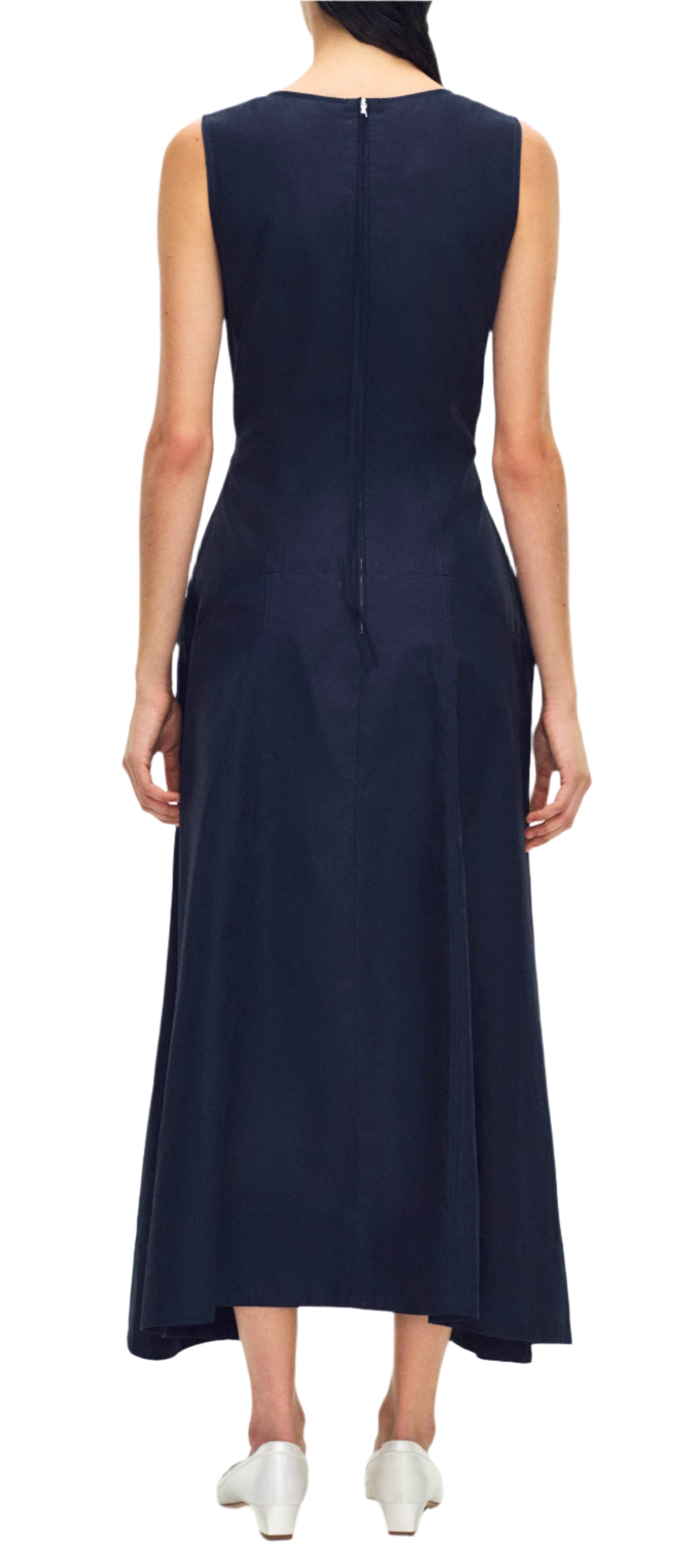 Someone dons the Adam Lippes Harlow Dress in rich navy cotton poplin, complemented by white shoes, enhancing their elegant ensemble as they face away.