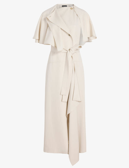 The Isolde Dress by Proenza Schouler is a cream, sleeveless, ankle-length dress in Viscose Twill with a trench-inspired draped cape, notch collar, and matching fabric belt at the waist.