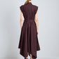 A woman stands facing away, wearing the Proenza Schouler Adinna Dress—a sleeveless dark purple dress with a waist belt and asymmetrical hem—paired with black sandals.