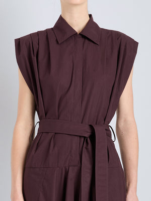 A person models the Proenza Schouler Adinna Dress—a sleeveless, collared, plum cotton shirting dress with a waist belt—against a plain light background.
