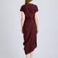 A woman faces away, wearing the Proenza Schouler Ren Printed Dot Dress in burgundy with black polka dots and black heels, set against a plain light gray background.