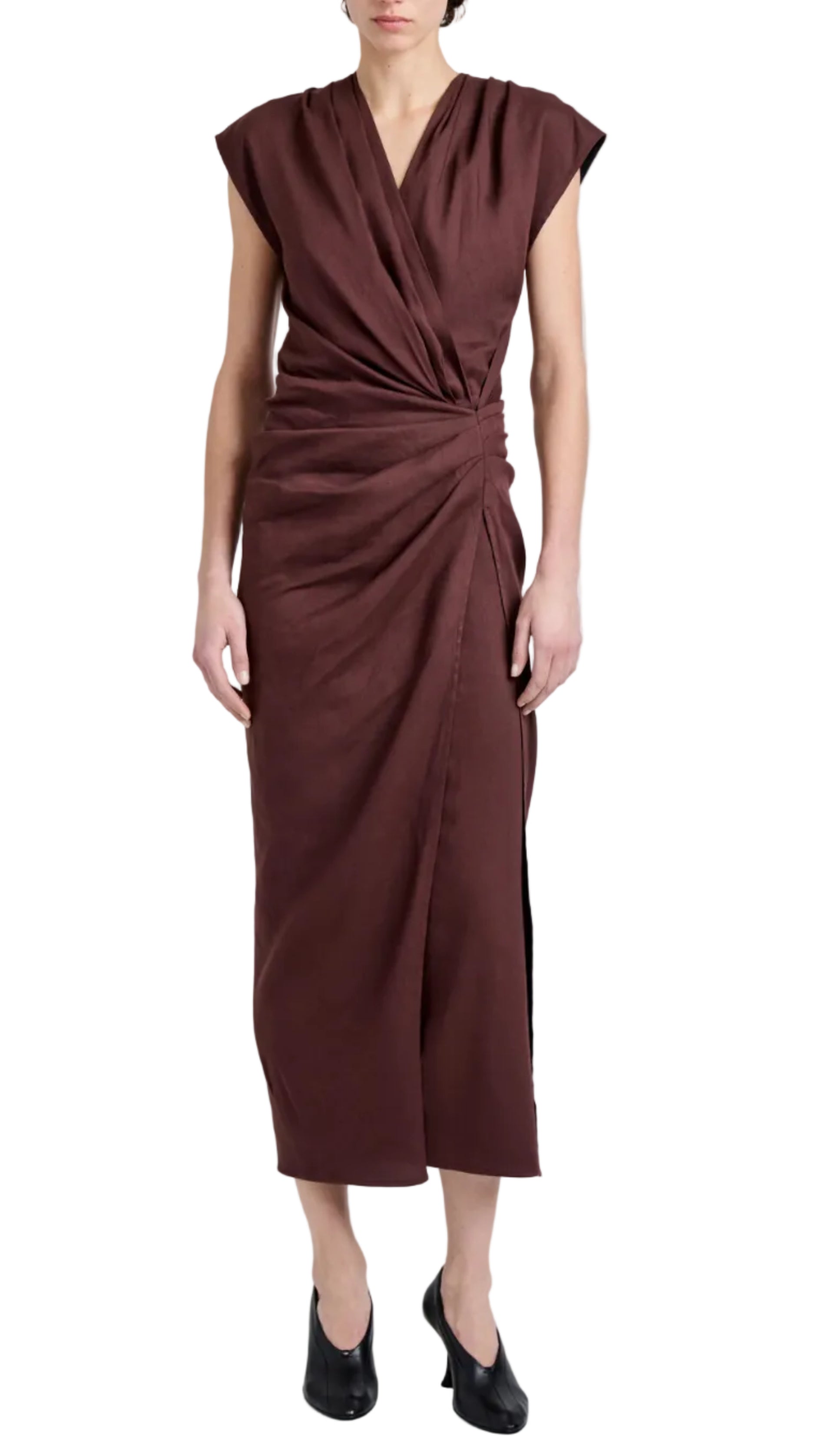 A person wearing the Bettina Dress by Proenza Schouler—a sleeveless brown wrap dress in Eco Stretch Viscose Linen with draped detailing and a side slit—paired with black heels.