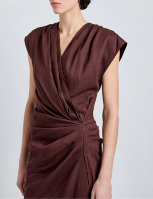 A person wearing the Proenza Schouler Bettina Dress, a sleeveless deep burgundy wrap made from Eco Stretch Viscose Linen with gathered waist detail, photographed from shoulders to mid-thigh.