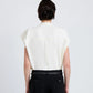 A person with dark hair styled in a low bun is shown from the back, wearing the Proenza Schouler Ranli Top—a white Matte Double Crepe sleeveless blouse with a draped collar—paired with black pants featuring a braided belt, set against a plain light background.