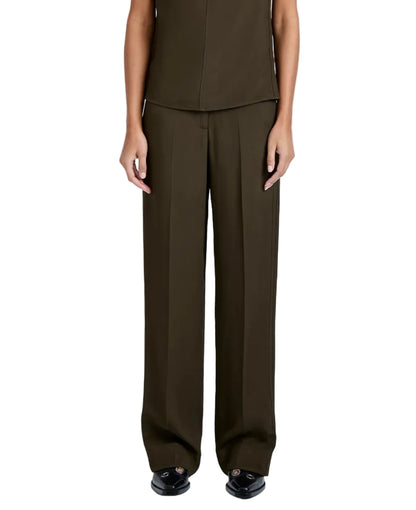 A person wears the Proenza Schouler Lien Pant in dark olive Eco Hammered Viscose, styled high-waisted and wide-leg, with black shoes. Arms are relaxed at their sides and the view is from the waist down.