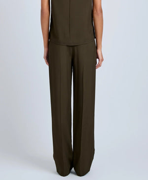 A person faces away from the camera, wearing the Proenza Schouler Lien Pant in high-waist olive green with a matching sleeveless Eco Hammered Viscose top, set against a plain light background.