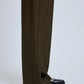 Someone wears the Proenza Schouler Lien Pant in dark olive, a high-waisted wide-leg style in eco hammered viscose that covers most of black square-toe shoes with metallic ring detail, set against a light neutral background.