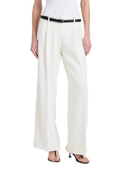 A person wearing the Proenza Schouler Halima Pant in white matte double crepe with pleats, styled with a black braided belt and black heeled sandals. Upper body is not shown.