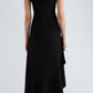 A person stands with their back to the camera against a plain light background, wearing the Proenza Schouler Elodine Tropical Wool Dress—a black, sleeveless, ankle-length piece with a transitional silhouette. Black shoes complete the look.