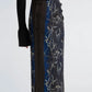 A person wears a black knit top with long sleeves and the Anais Skirt by Proenza Schouler—an ankle-length, slim-fit piece featuring a blue and black floral print reminiscent of Brazilian night orchids.