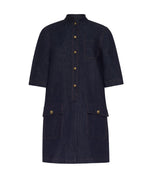 The Lauder Dress by Adam Lippes is a dark Japanese indigo denim, knee-length dress featuring short sleeves, topstitching accents, front buttons, a chest pocket, and two large front flap pockets with antique matte gold closures.