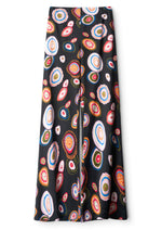 Staud’s Stroll Silk Pant features an effortless drape and a flared cut, adorned with a colorful, abstract concentric circle pattern in red, orange, blue, green, and white.