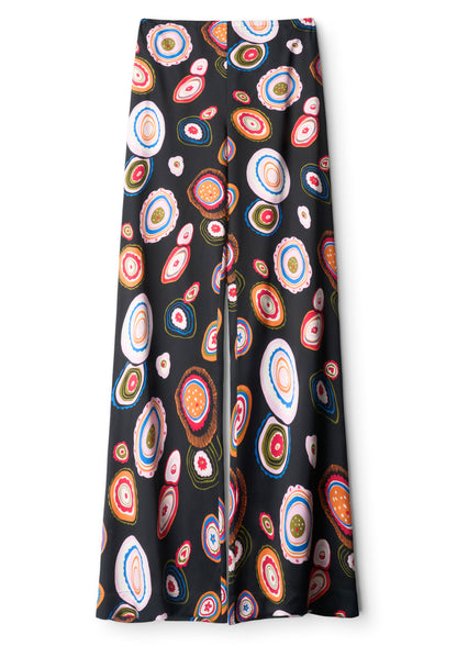 Staud’s Stroll Silk Pant features an effortless drape and a flared cut, adorned with a colorful, abstract concentric circle pattern in red, orange, blue, green, and white.