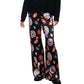 Dressed in the Staud Stroll Silk Pant—black wide-leg trousers adorned with a colorful circular print—paired with a black long-sleeve top and black shoes, this effortlessly chic look is elevated by the fluid drape of the silk.