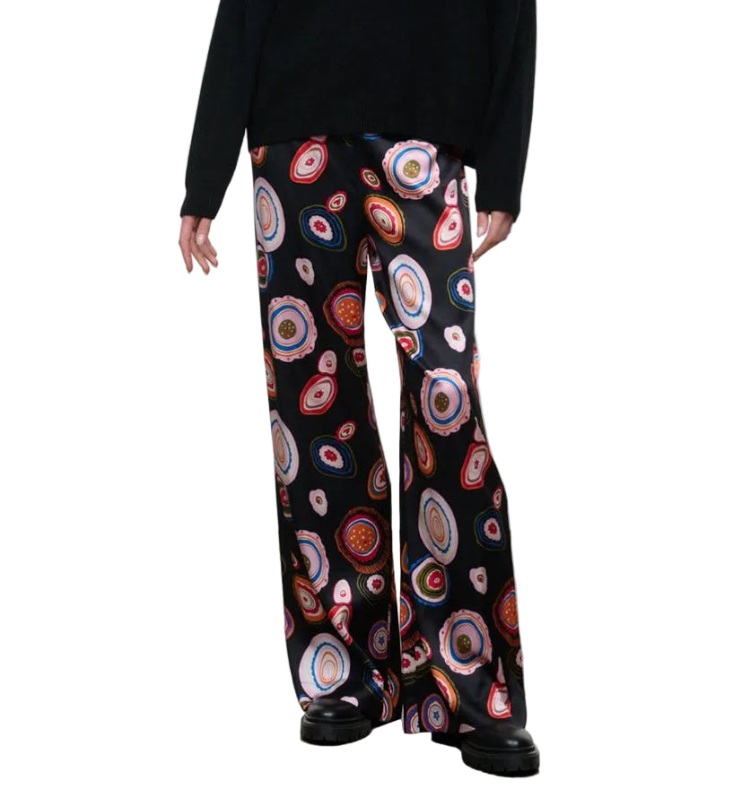 Dressed in the Staud Stroll Silk Pant—black wide-leg trousers adorned with a colorful circular print—paired with a black long-sleeve top and black shoes, this effortlessly chic look is elevated by the fluid drape of the silk.