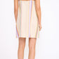 A woman stands facing away in the Staud Laura Linen Mini Dress, featuring summer stripes and spaghetti straps, paired with flat beige shoes against a plain white background.