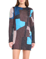 A woman wears the Staud Kona Dress, a long-sleeve textured mini featuring an abstract geometric pattern in blue, black, brown, and beige.