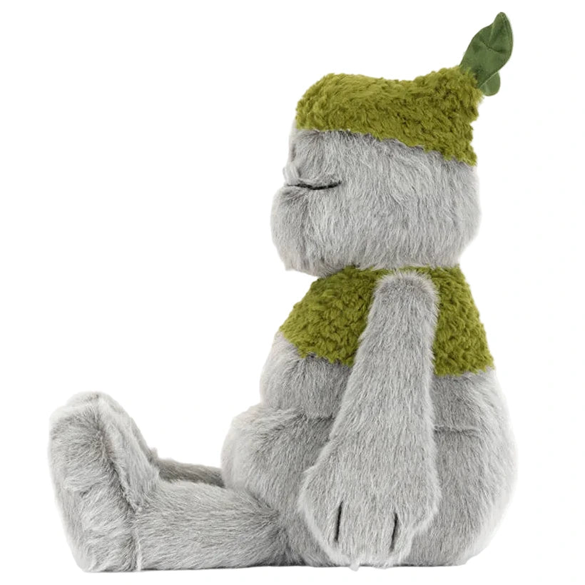 The Jellycat Rockleton plush toy sits upright with closed eyes, wearing a green textured hat with a leaf and a matching vest.