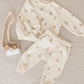 A cream Rylee & Cru Baby Boys' and Boys' Sweatshirt with sailboat print is displayed beside a wooden toy camera with beige strap on a light beige fabric background.
