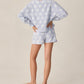 A person stands barefoot with hands on hips, wearing the Rylee & Cru Teen Girls' Karli Set in light blue with white daisies, photographed from behind against a plain background.